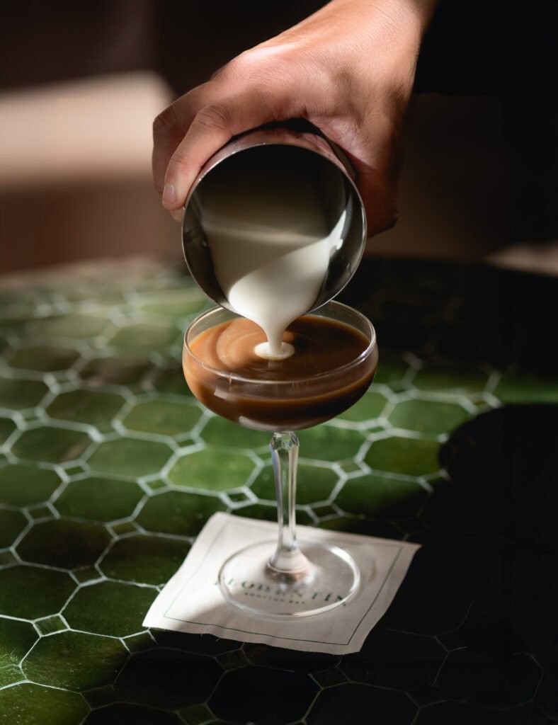 Cream pouring into an espresso cocktail on a green tiled table at Florentin