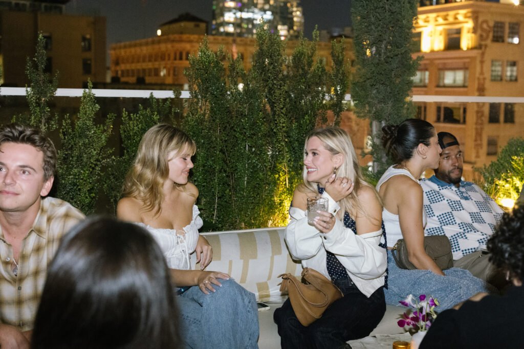 Two friends sharing drinks on the rooftop at night